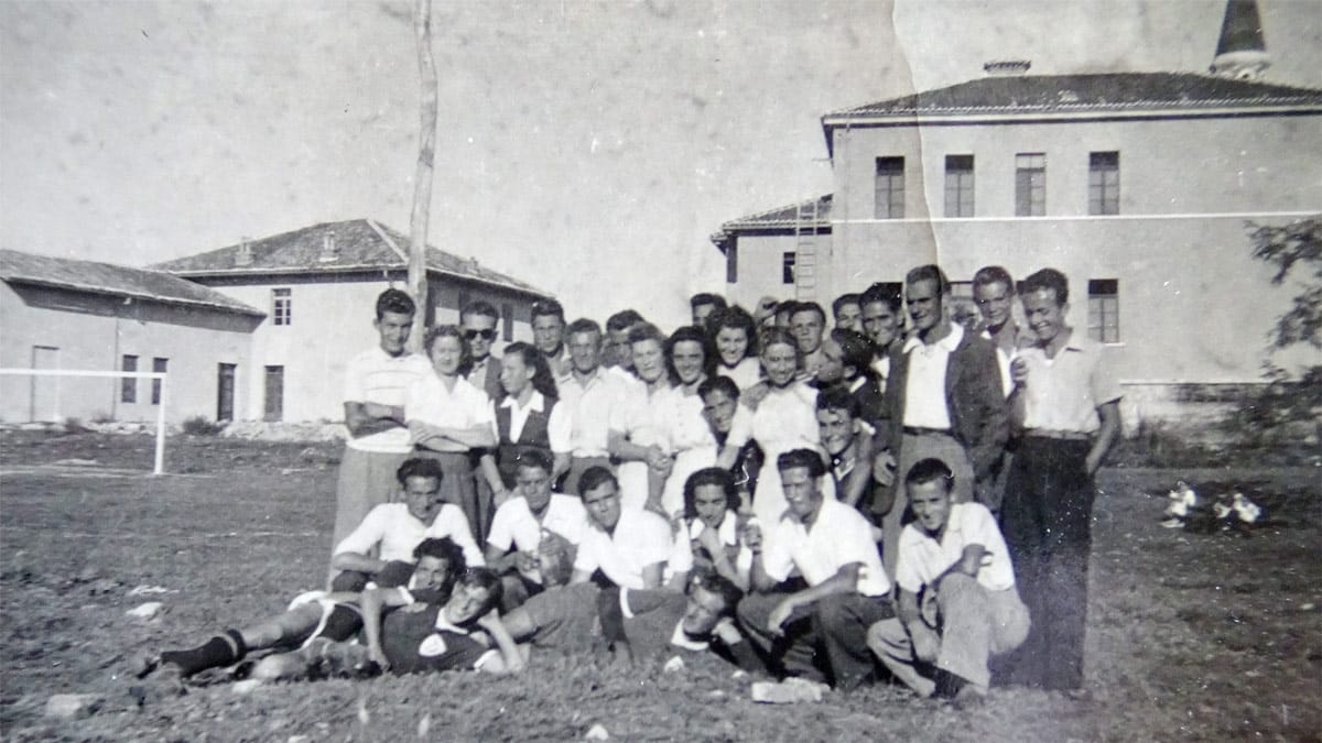 foto 6 -  Igrišče za šolo. Skupina vaščanov takoj po zaključeni tekmi. V ozadju je videti zvonik ter stavbi današnje srednje in osnovne šole. V ozadju so vidna vrata, v katera sem kot otrok rad streljal in oponašal argentinskega asa Sivorija.