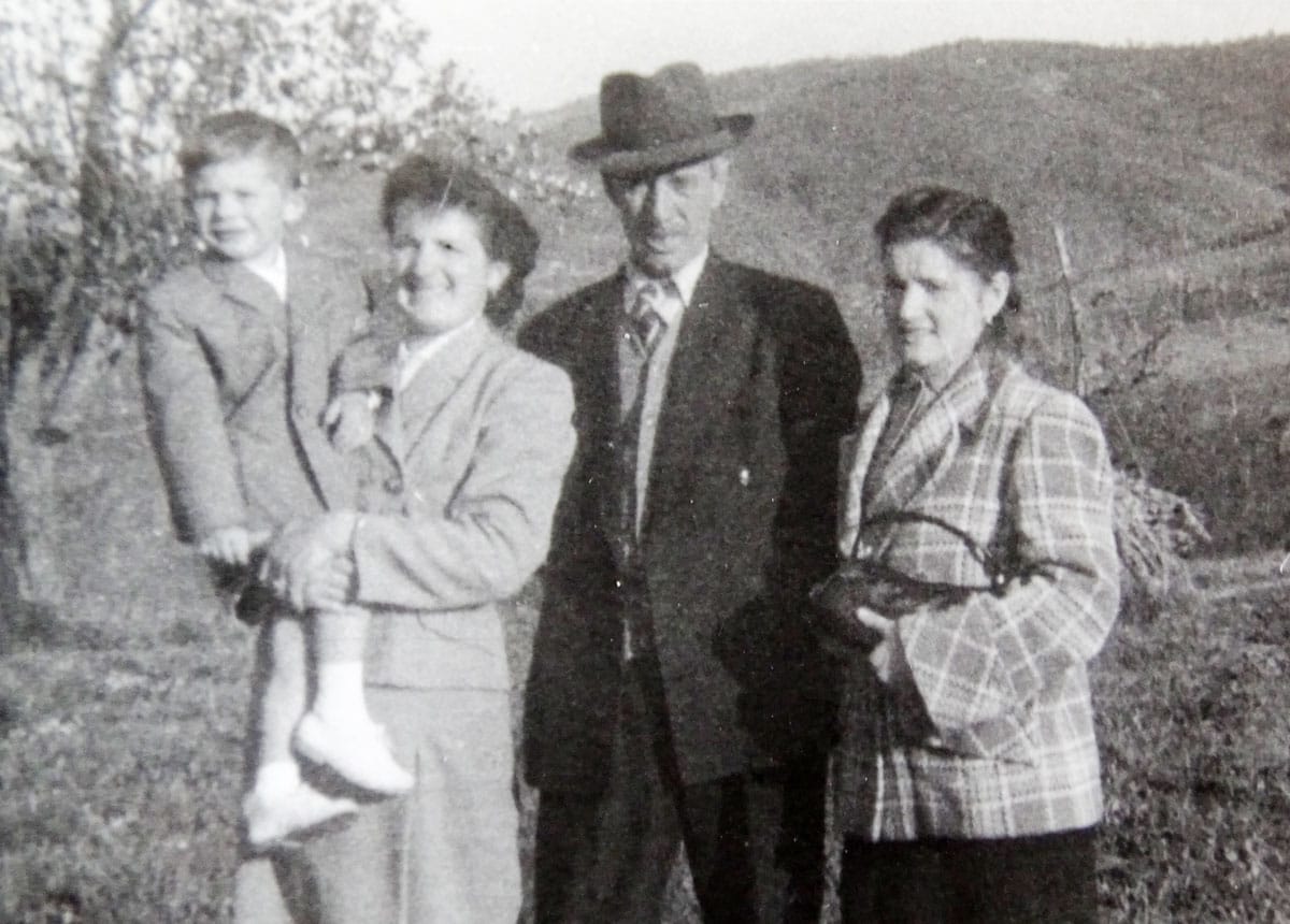 Foto 3 - V maminem naročju v Vipolžah. Ob njej je še nono Franc Rožič in sestra Judita. V ozadju priljubljeni briški griči.
